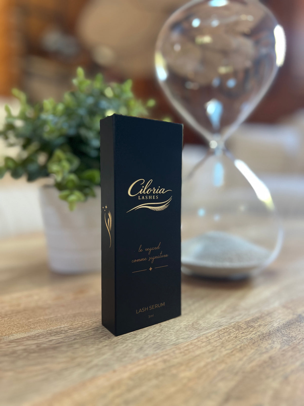 "Sérum cils Ciloria Lashes posé sur une table en bois avec sablier"